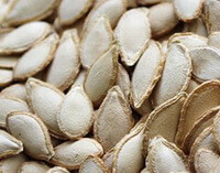 de nombreuses graines de citrouille blanchâtres séchées sont empilées ensemble