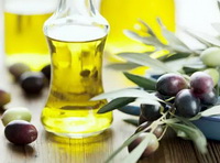 several bottles of light yellow olive oil and olive fruit with leaves