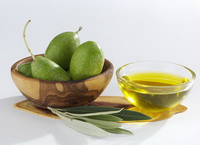 several green olive fruits in a bowl and a glass bowl of olive oil,with several green olive leaves