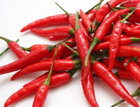 many thin red peppers are piled together